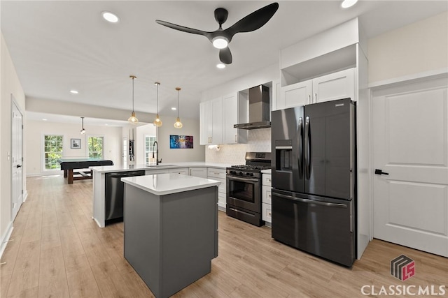 kitchen with pendant lighting, wall chimney range hood, sink, appliances with stainless steel finishes, and kitchen peninsula