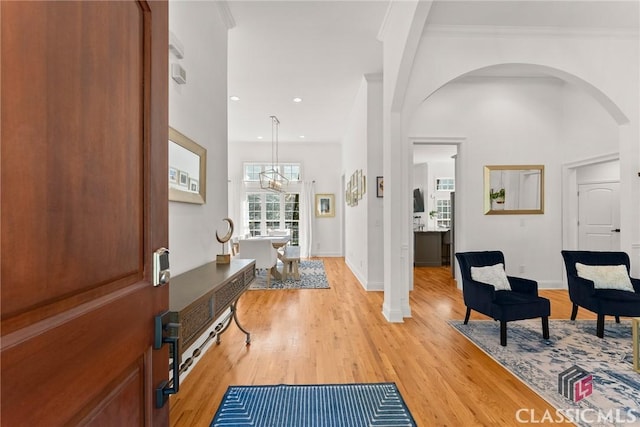 foyer with light hardwood / wood-style floors, ornamental molding, and an inviting chandelier