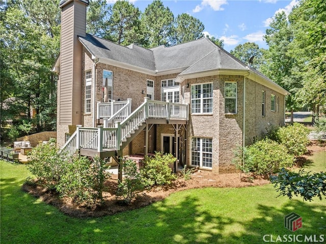 rear view of house featuring a lawn and a wooden deck