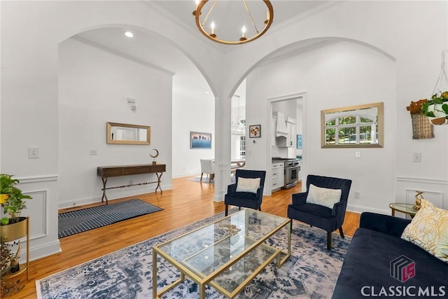 living room featuring light hardwood / wood-style floors, ornamental molding, and an inviting chandelier