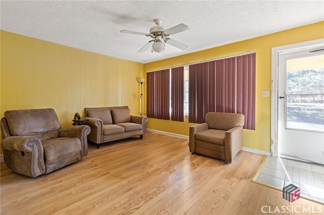 living room featuring ceiling fan, a textured ceiling, and light wood-type flooring