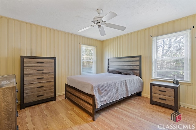 bedroom with ceiling fan, light hardwood / wood-style floors, and a textured ceiling