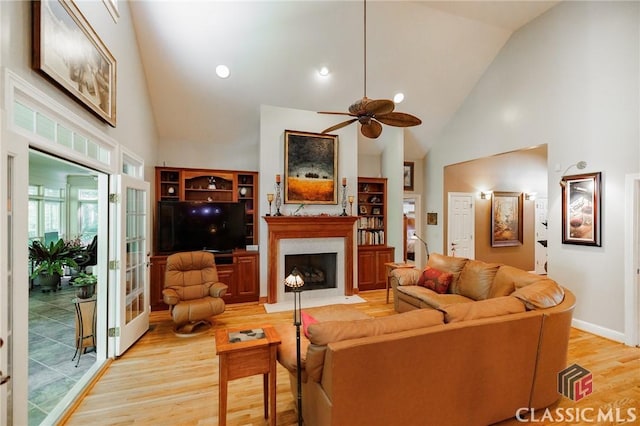 living room with ceiling fan, high vaulted ceiling, and light hardwood / wood-style flooring