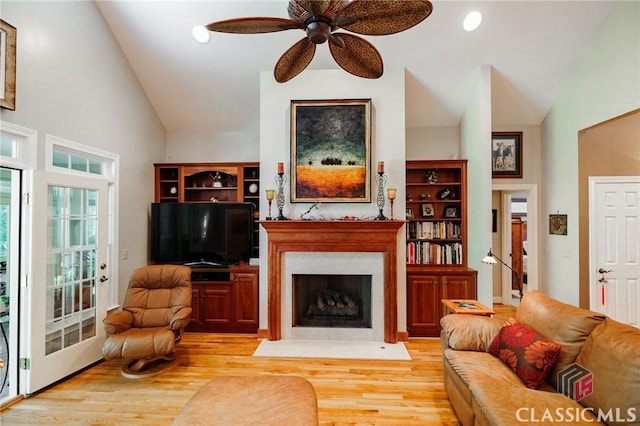 living room with ceiling fan, light hardwood / wood-style floors, and high vaulted ceiling