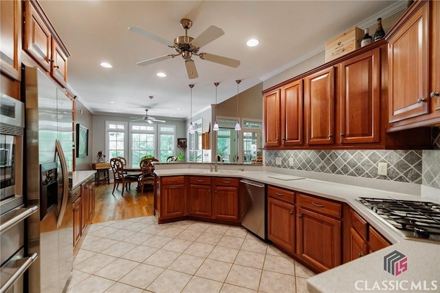 kitchen featuring kitchen peninsula, ornamental molding, stainless steel appliances, ceiling fan, and decorative light fixtures