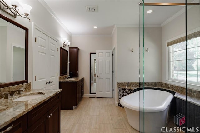 bathroom with a bathtub, crown molding, and vanity