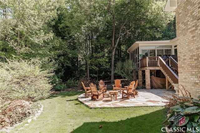 view of yard featuring a patio, a fire pit, and a sunroom