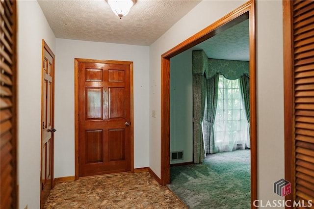 hallway featuring carpet flooring and a textured ceiling