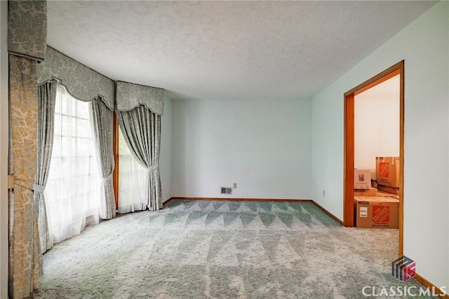 unfurnished room featuring carpet and a textured ceiling