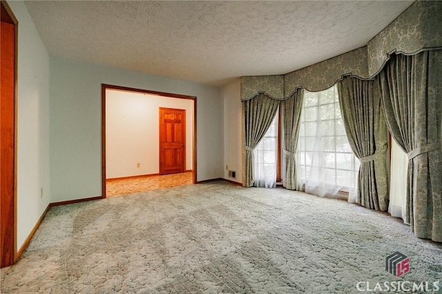 unfurnished room with light colored carpet and a textured ceiling