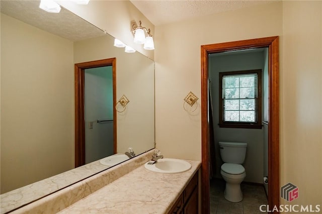 bathroom with tile patterned flooring, a textured ceiling, vanity, and toilet