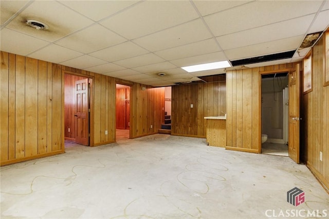 basement with wood walls and a drop ceiling