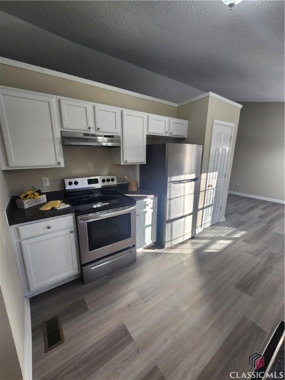 kitchen featuring appliances with stainless steel finishes, a textured ceiling, vaulted ceiling, sink, and light hardwood / wood-style flooring