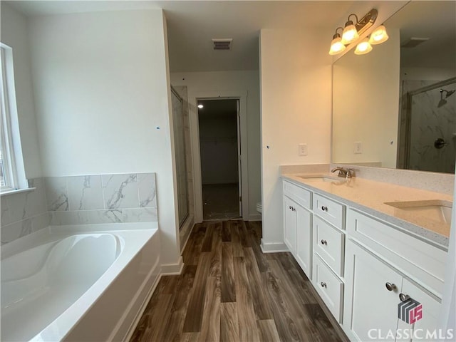 full bathroom with vanity, toilet, wood-type flooring, and independent shower and bath