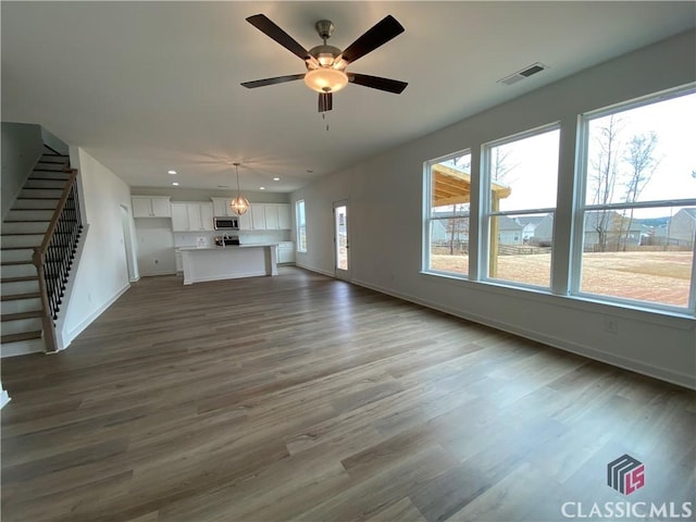 unfurnished living room with ceiling fan, plenty of natural light, and dark hardwood / wood-style floors