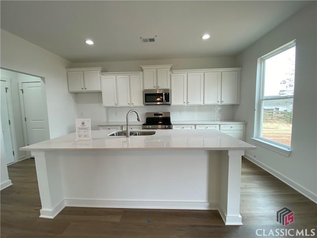 kitchen with a center island with sink, white cabinets, and stainless steel appliances