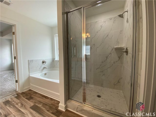 bathroom featuring wood-type flooring and separate shower and tub