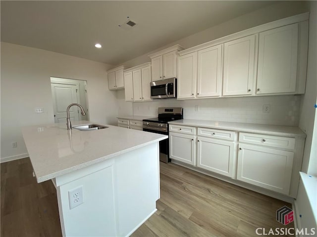 kitchen with white cabinets, stainless steel appliances, a kitchen island with sink, and sink