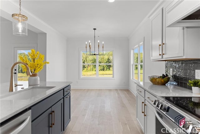 kitchen with white cabinets, sink, hanging light fixtures, light stone counters, and stainless steel appliances