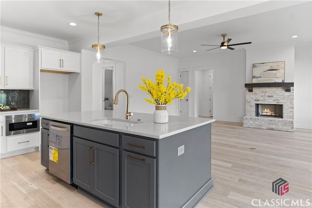 kitchen with gray cabinetry, sink, stainless steel appliances, a center island with sink, and white cabinets