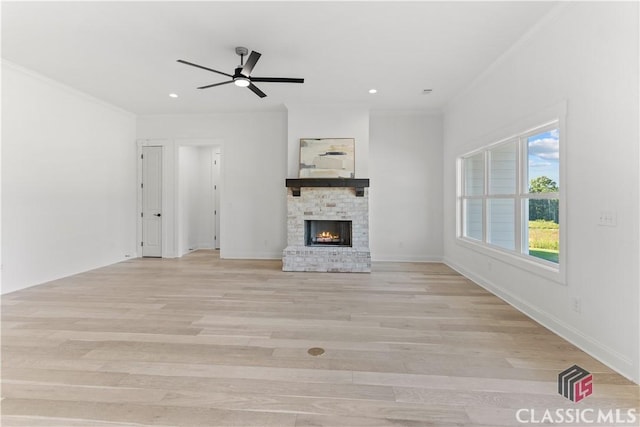 unfurnished living room with ceiling fan, crown molding, light wood-type flooring, and a fireplace