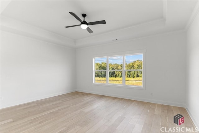 empty room featuring a raised ceiling, ceiling fan, crown molding, and light hardwood / wood-style floors