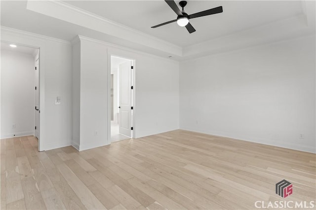 spare room with ceiling fan, light wood-type flooring, ornamental molding, and a tray ceiling