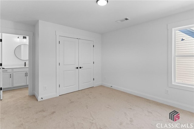 unfurnished bedroom with connected bathroom, a closet, and light colored carpet