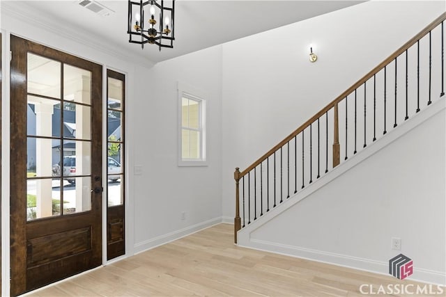 entryway featuring a chandelier, ornamental molding, and light hardwood / wood-style flooring