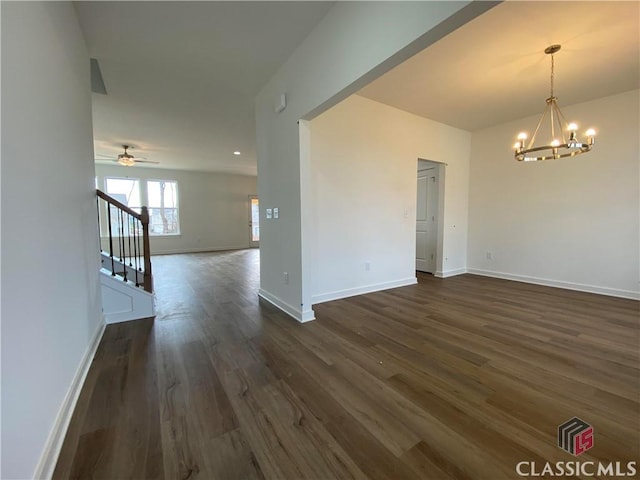 unfurnished room with ceiling fan with notable chandelier and dark wood-type flooring