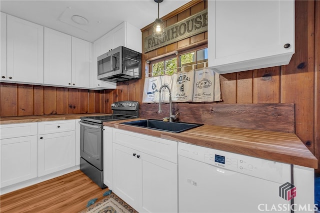 kitchen featuring white dishwasher, sink, pendant lighting, white cabinetry, and range with electric stovetop