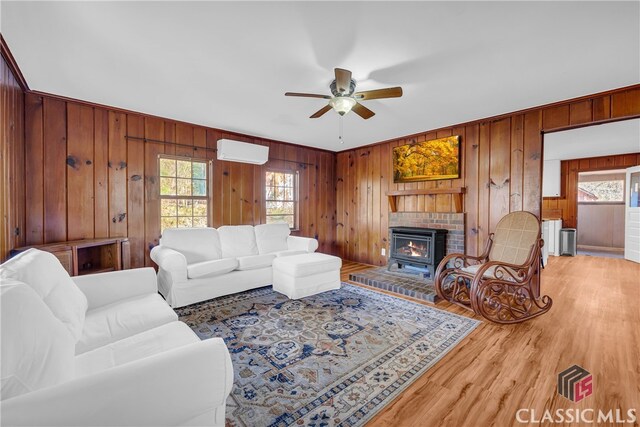 living room with a wall mounted AC, ceiling fan, and wood walls