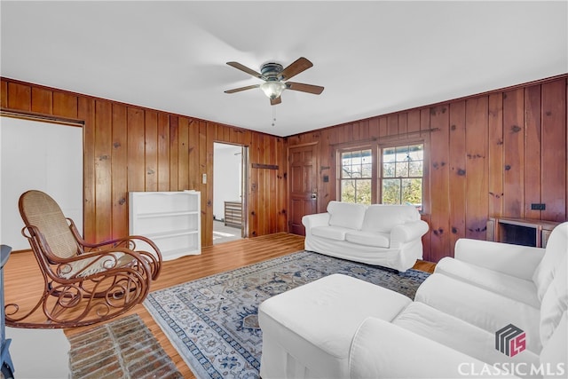 living room featuring hardwood / wood-style flooring, ceiling fan, and wooden walls