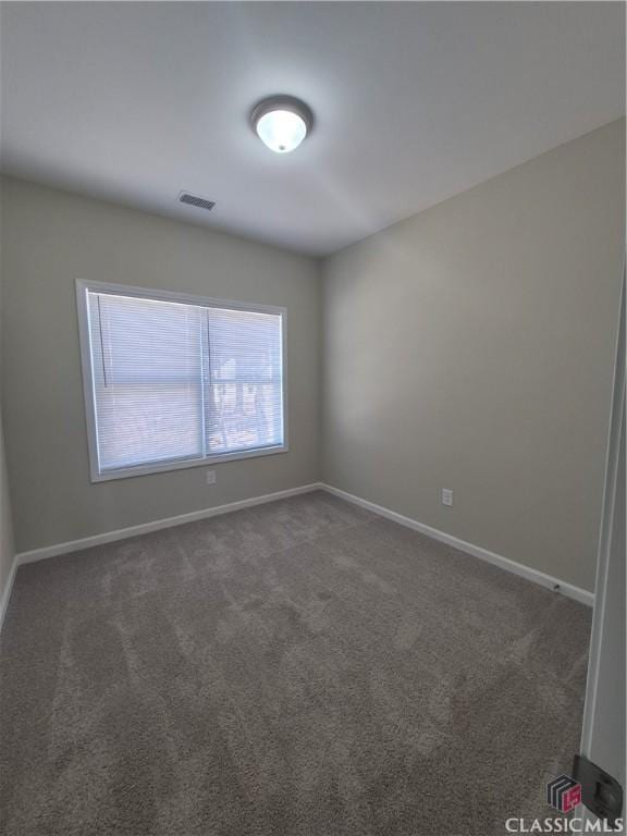 unfurnished room featuring dark colored carpet