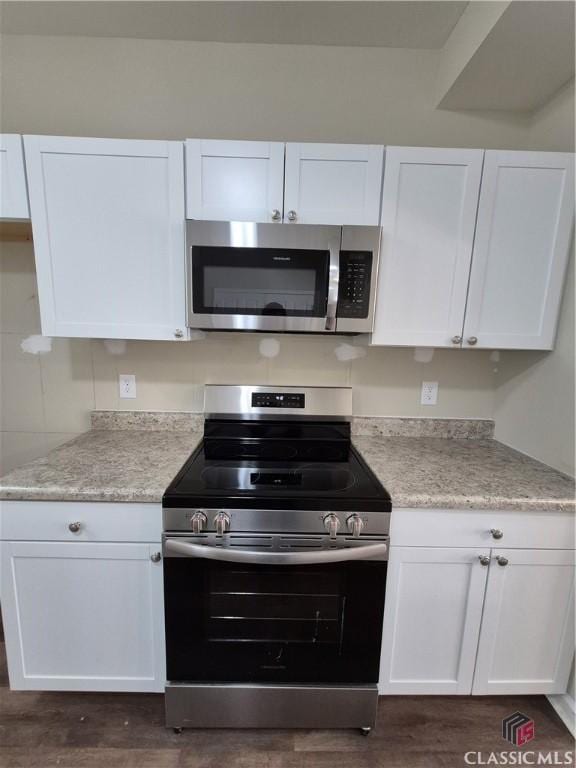 kitchen with white cabinets, dark wood-type flooring, and appliances with stainless steel finishes