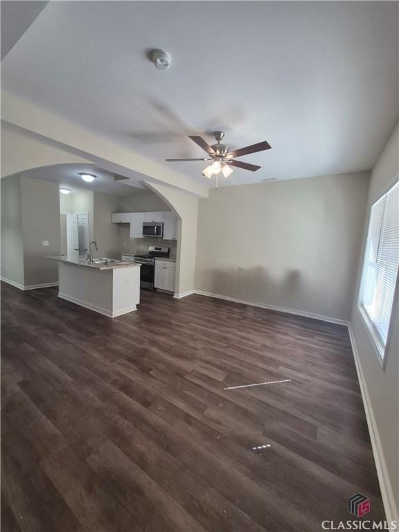 unfurnished living room featuring ceiling fan, sink, and dark wood-type flooring