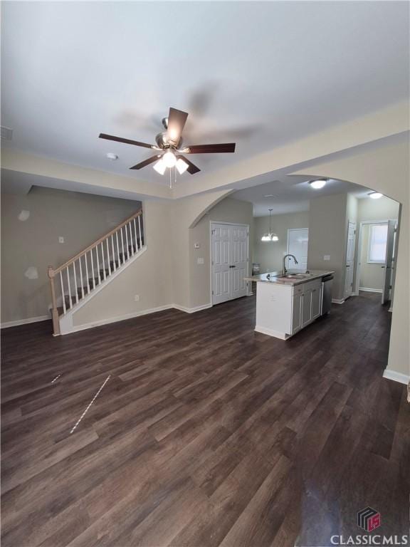 unfurnished living room with ceiling fan with notable chandelier, dark hardwood / wood-style flooring, and sink