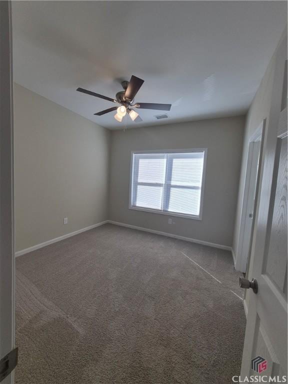 empty room with dark colored carpet and ceiling fan