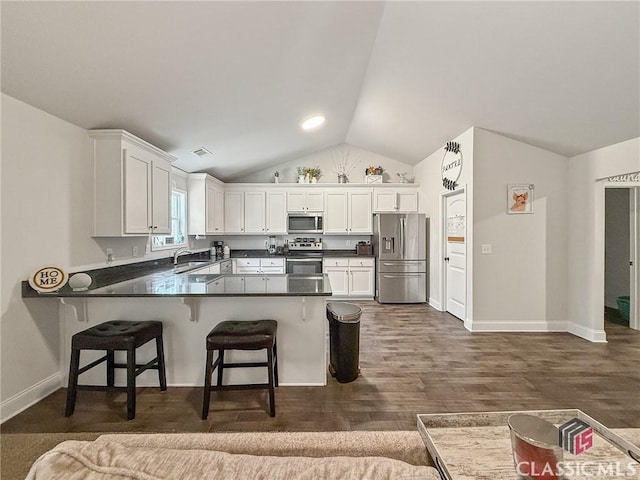 kitchen featuring stainless steel appliances, white cabinets, a kitchen breakfast bar, and kitchen peninsula