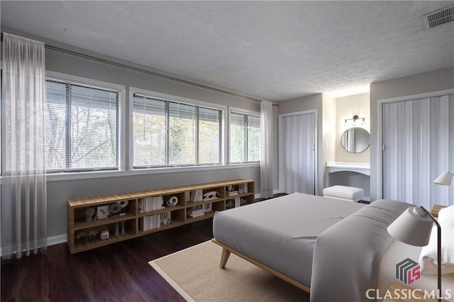 bedroom featuring a textured ceiling, multiple windows, and dark hardwood / wood-style floors