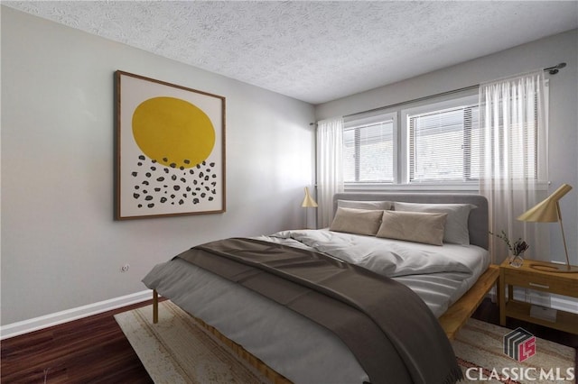 bedroom with a textured ceiling and dark wood-type flooring