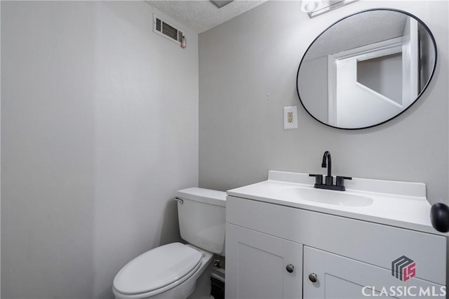 bathroom with toilet, vanity, and a textured ceiling