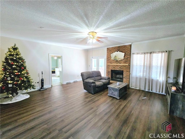 living room with crown molding, plenty of natural light, dark wood-style flooring, and a fireplace