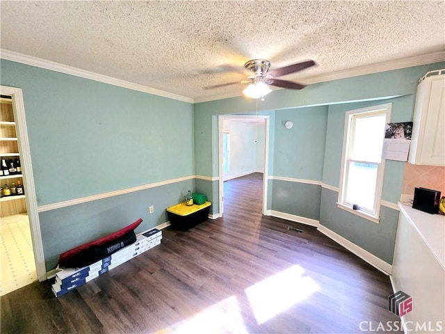 unfurnished room featuring crown molding, a textured ceiling, baseboards, and wood finished floors