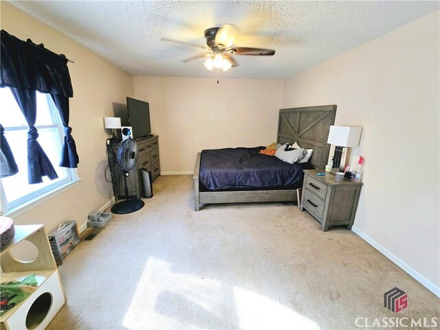 bedroom featuring light carpet, a textured ceiling, a ceiling fan, and baseboards