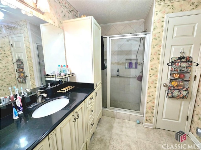 bathroom with wallpapered walls, vanity, a textured ceiling, and a stall shower