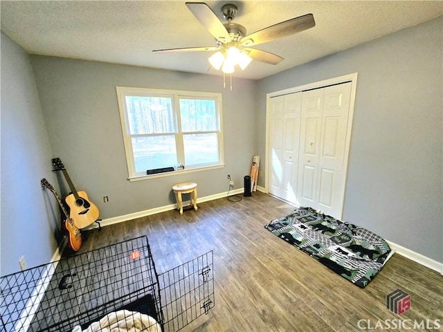 misc room with ceiling fan, a textured ceiling, baseboards, and wood finished floors