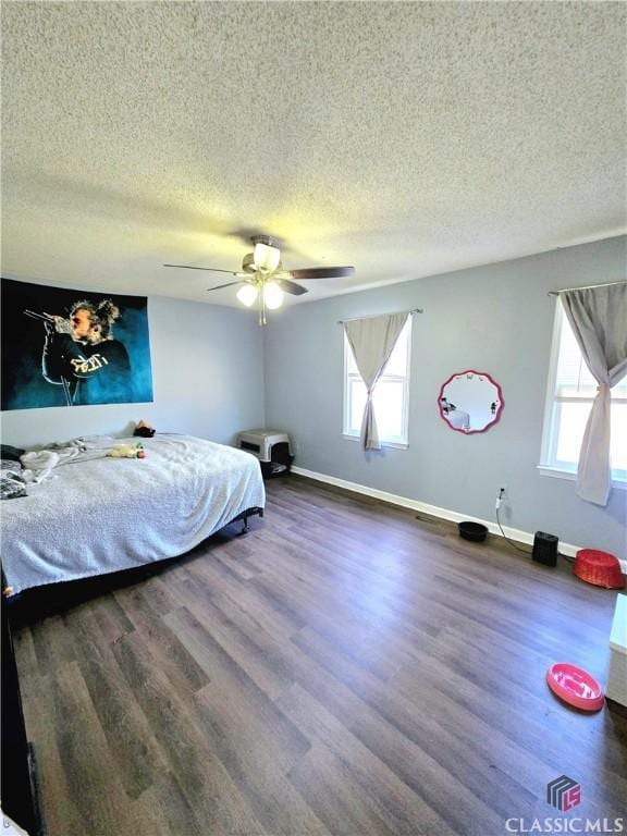 unfurnished bedroom with ceiling fan, a textured ceiling, wood finished floors, and baseboards