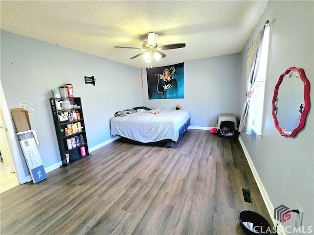 bedroom with a ceiling fan, a textured ceiling, baseboards, and wood finished floors