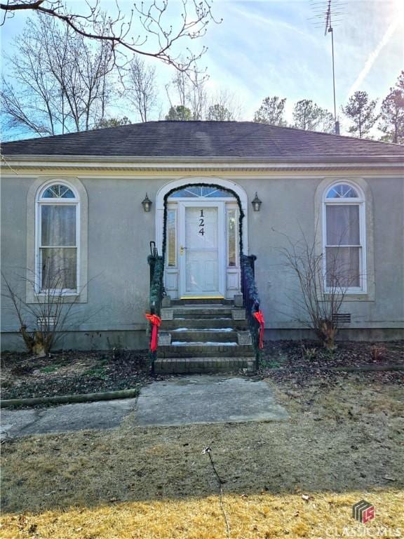 view of front facade featuring a shingled roof and stucco siding